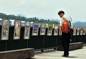 游客仔细观看法轮功学员的摄影作品展